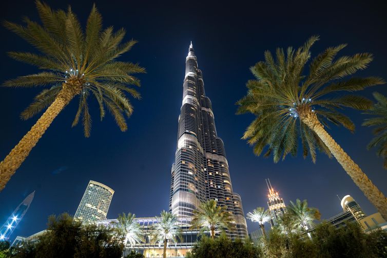 Burj Khalifa illuminated at night, surrounded by palm trees in Dubai