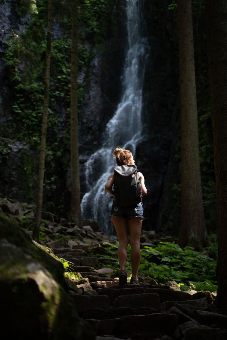 Hiker on rocky path near waterfall in Baden-Württemberg, Germany.