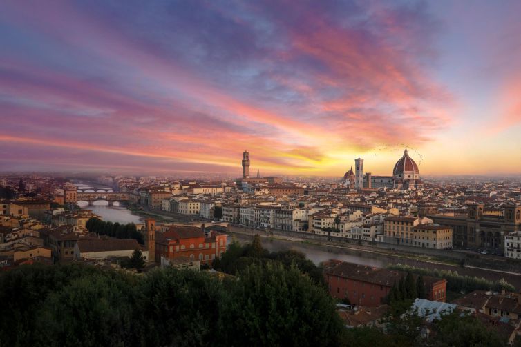 Panoramic view of Florence at sunset, featuring the River Arno and iconic architecture.