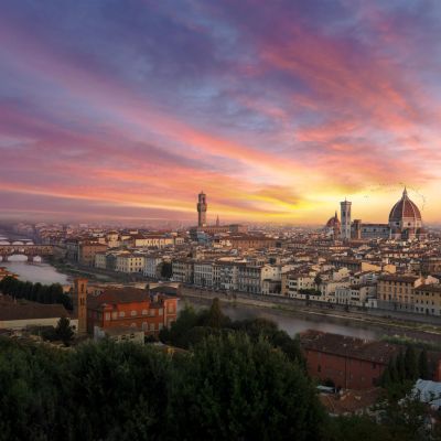 Panoramic view of Florence at sunset, featuring the River Arno and iconic architecture.