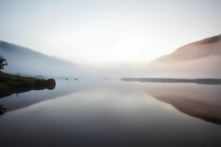 Foggy lake reflecting dawn light and misty hills in Norway