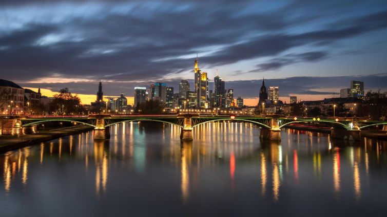 Frankfurt skyline at twilight, featuring vibrant reflections on the Main River.