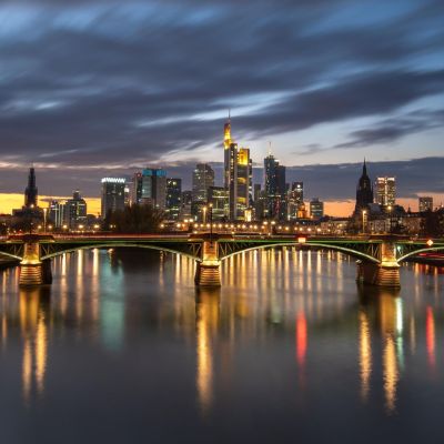 Frankfurt skyline at twilight, featuring vibrant reflections on the Main River.