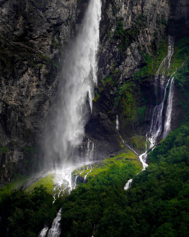 Waterfall cascading down rocky cliffs surrounded by greenery in Geiranger, Norway.