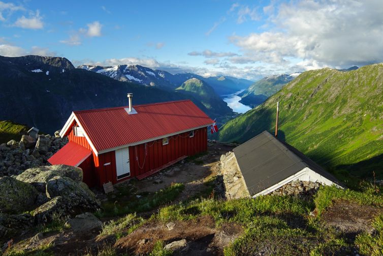 Red cabin in Norway's Vestland region with mountains and fjord in the background