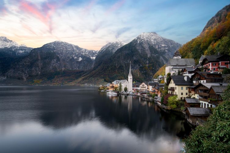 Peaceful Hallstatt village reflecting in the lake against mountainous backdrop in Austria.