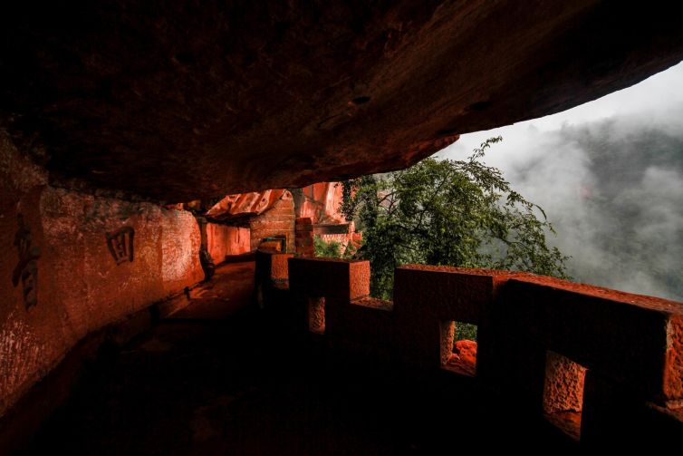 Misty view of rock formations and ancient shrines in Yibin, Sichuan, China.