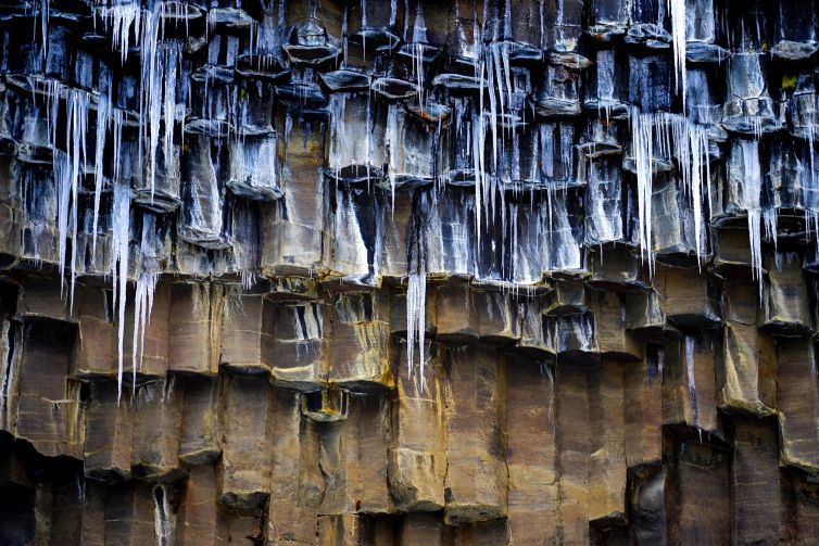 Icicles hanging from rugged cliffs in Fagurhólsmýri, Iceland.