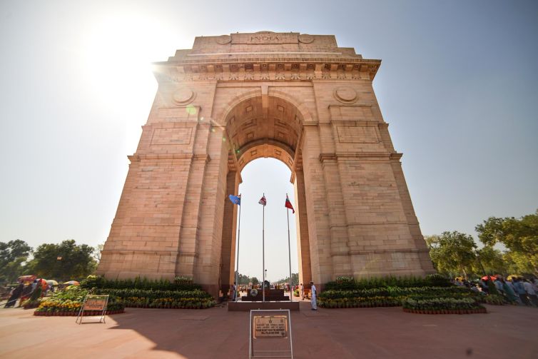 India Gate monument in New Delhi, showcasing grand architecture and flags.