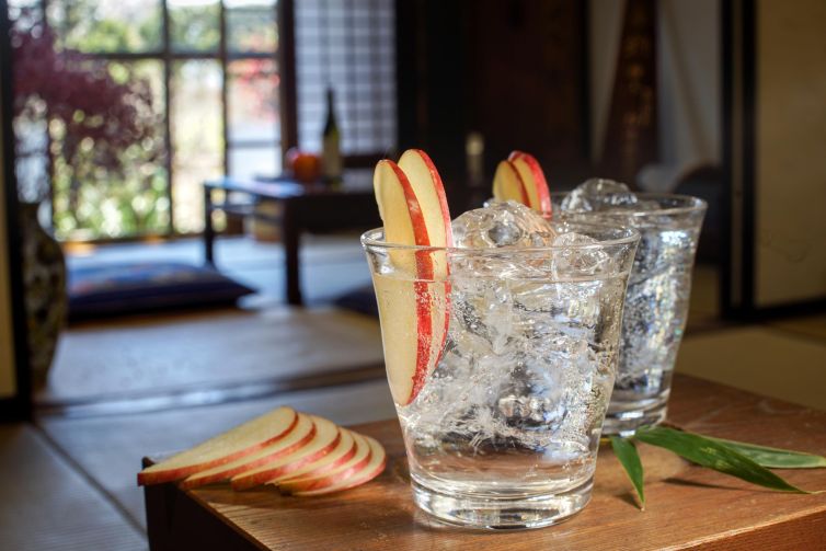 Two sparkling glasses adorned with apple slices in a serene Japanese home environment.