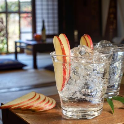 Two sparkling glasses adorned with apple slices in a serene Japanese home environment.