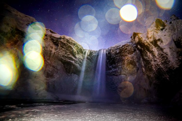 Iceland waterfall illuminated by night sky with starry backdrop