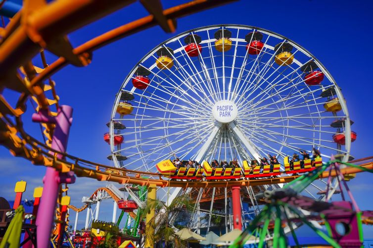Colorful view of Pacific Park with Ferris wheel and roller coaster in Santa Monica, California.