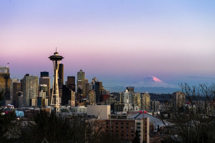 Seattle skyline at sunset featuring the Space Needle and Mt. Rainier in the background.