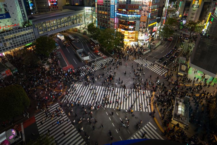 Aerial view of Shibuya Crossing in Tokyo, showcasing a crowd of pedestrians at night.