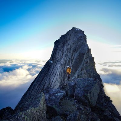 Dramatic mountain peak in Kjøpsvik, Norway set against a clear sky and clouds.