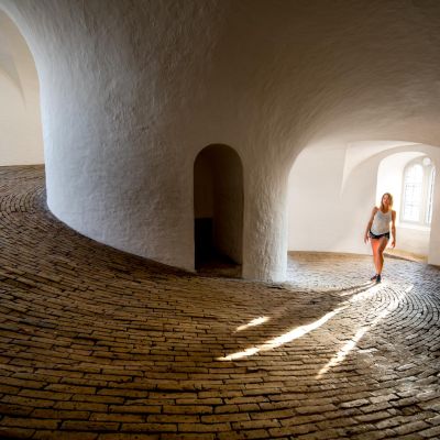 Woman walking on a winding brick path in a bright, curved interior in Copenhagen.