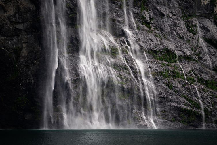 Waterfall cascading down rugged cliffs in Geiranger, Norway.