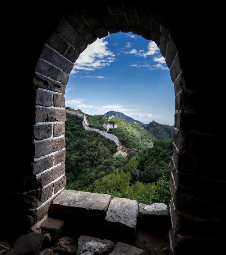 View of the wild Jiankou section of the Great Wall of China through a stone arch.
