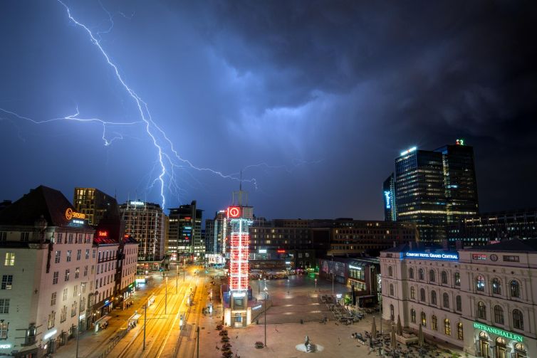 Stormy night over Oslo with dramatic lightning bolts illuminating the skyline.