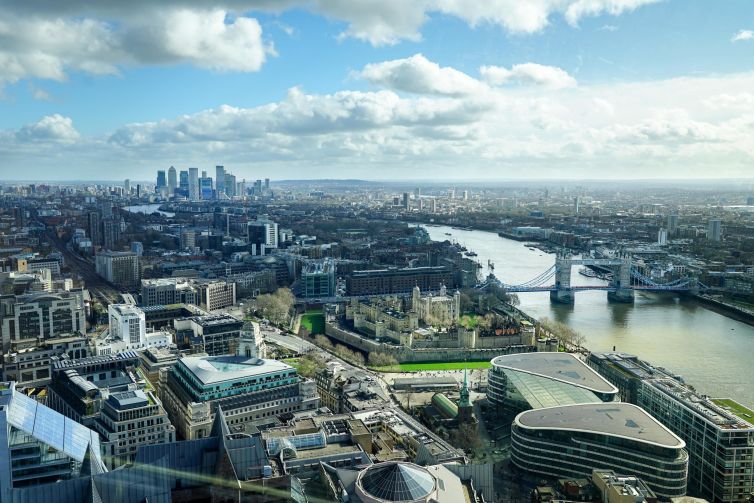 Aerial view of London skyline featuring the Thames River, Tower Bridge, and urban landscapes.