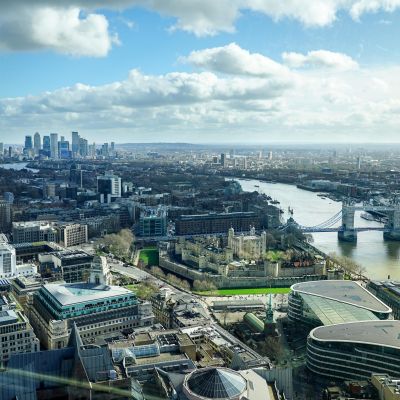 Aerial view of London skyline featuring the Thames River, Tower Bridge, and urban landscapes.