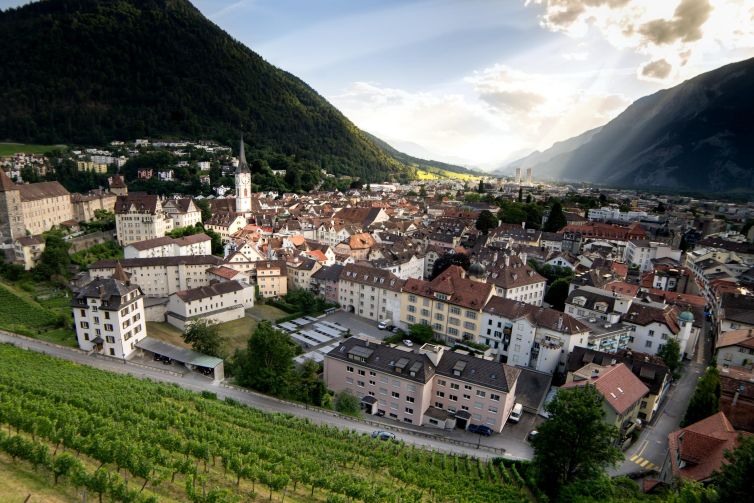 Aerial view of Chur, Switzerland with vineyards and mountains in the background.
