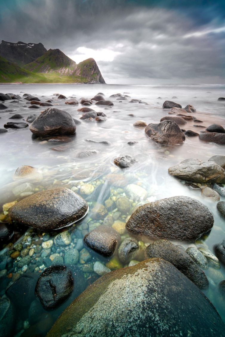 Bøstad landscape in Nordland, Norway with stones by a peaceful shore.