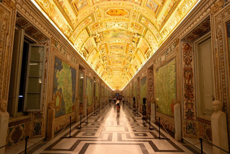 Ornate corridor in Vatican City showcasing vibrant murals and historic architecture.
