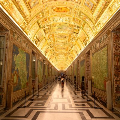Ornate corridor in Vatican City showcasing vibrant murals and historic architecture.